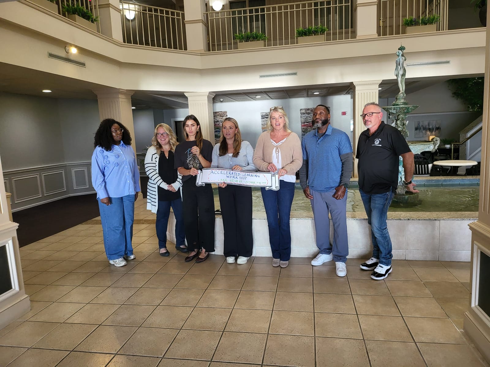 The October 2024 workshop cohort posing together in the hotel atrium